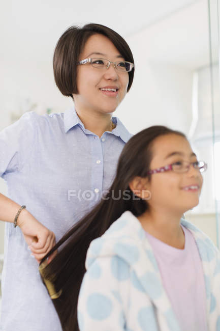 Mère brossant les cheveux filles — Photo de stock