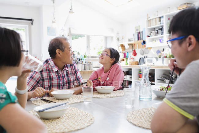 Родина багатьох поколінь їсть локшину з паличками за столом — стокове фото