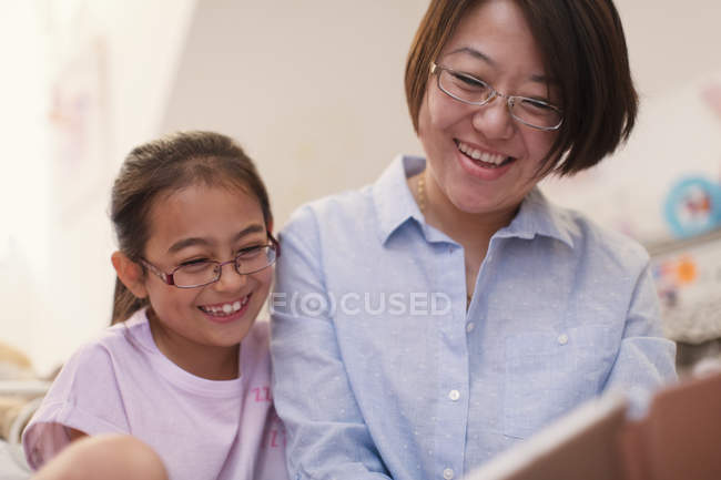 Madre e hija sonrientes leyendo - foto de stock
