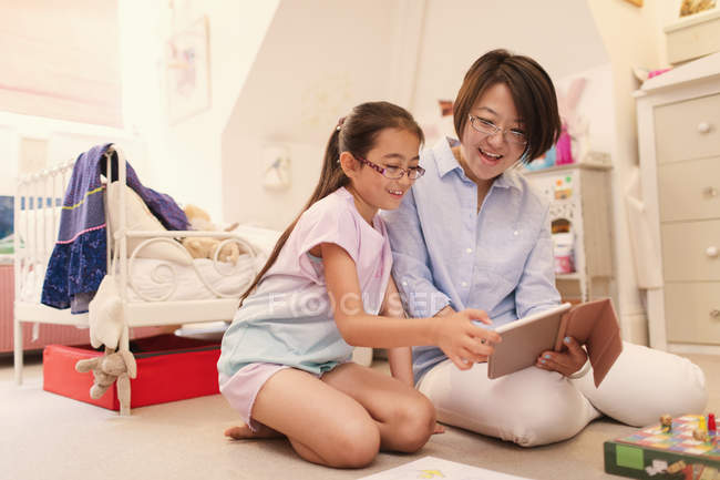 Mother and daughter using digital tablet on living room floor — Stock Photo