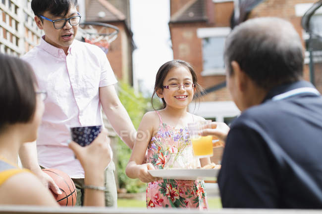 Petite-fille servant du jus d'orange à grand-père dans la cour arrière — Photo de stock