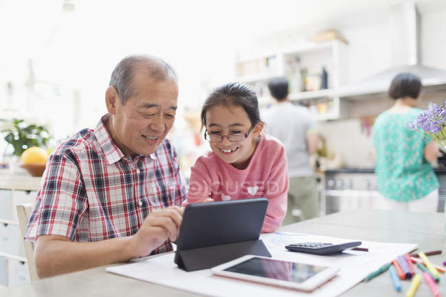 Grandfather and granddaughter using digital tablet in kitchen — Stock Photo