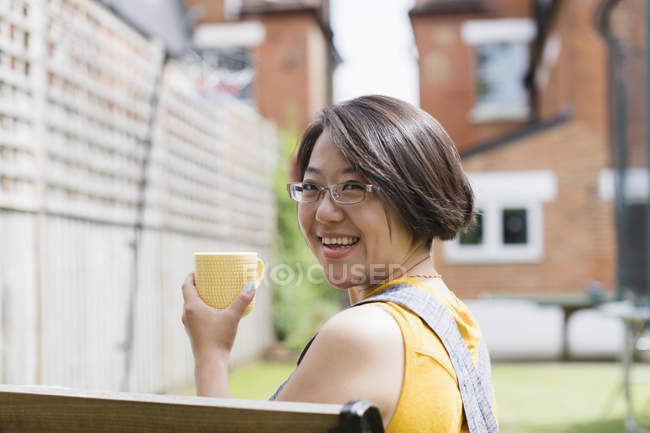 Portrait femme souriante buvant du thé dans la cour ensoleillée — Photo de stock