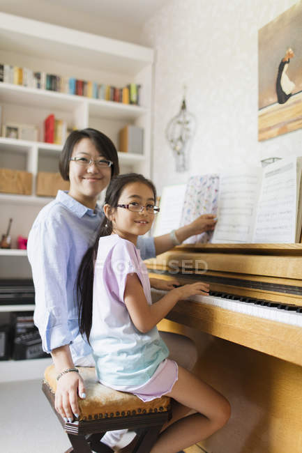 Ritratto madre e figlia sorridenti che suonano il pianoforte — Foto stock