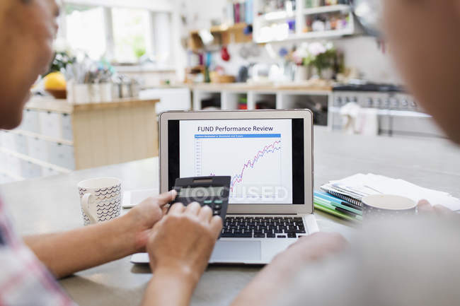 Senior man with calculator looking at investment chart on laptop — Stock Photo