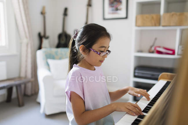Chica tocando el piano en interiores - foto de stock