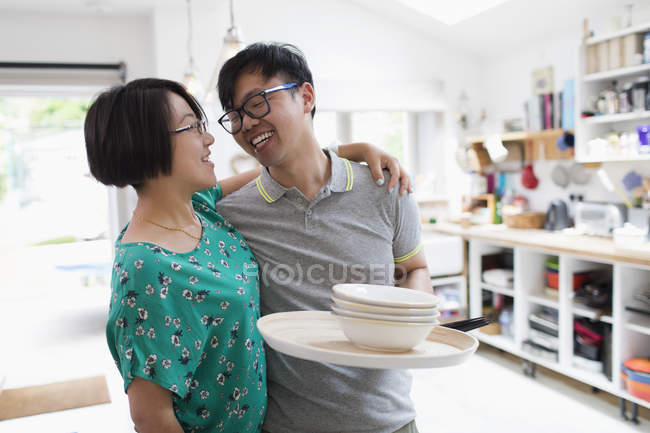 Ласковая пара обнимается, моет посуду на кухне — стоковое фото