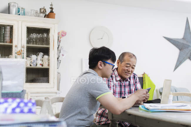 Son helping senior father paying bills at laptop — Stock Photo