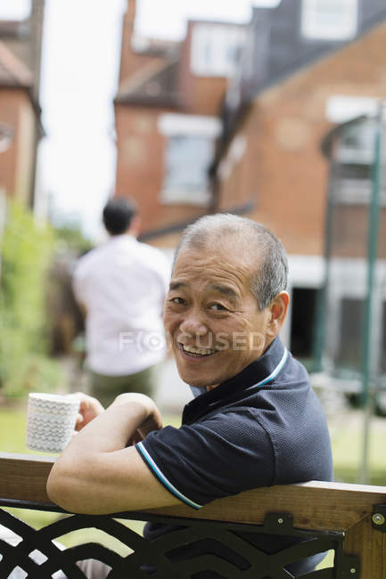 Porträt lächelnder älterer Mann trinkt Tee im Hof — Stockfoto