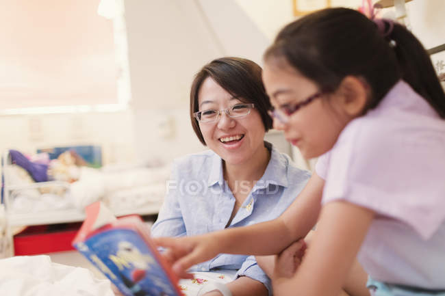 Mère et fille lecture livre dans la chambre — Photo de stock