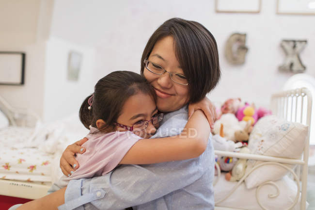 Affectionate mother and daughter hugging in bedroom — Stock Photo