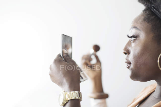 Mujer aplicando maquillaje en espejo compacto - foto de stock