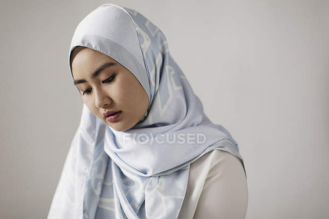 Mujer joven y serena usando hijab de seda azul - foto de stock