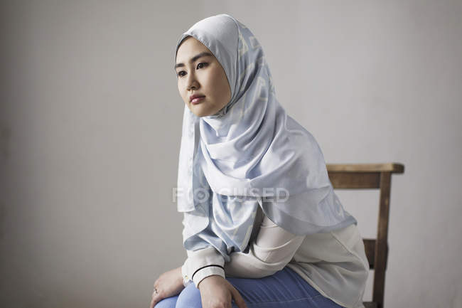 Задумчивая молодая женщина в синем шелковом хиджабе — стоковое фото
