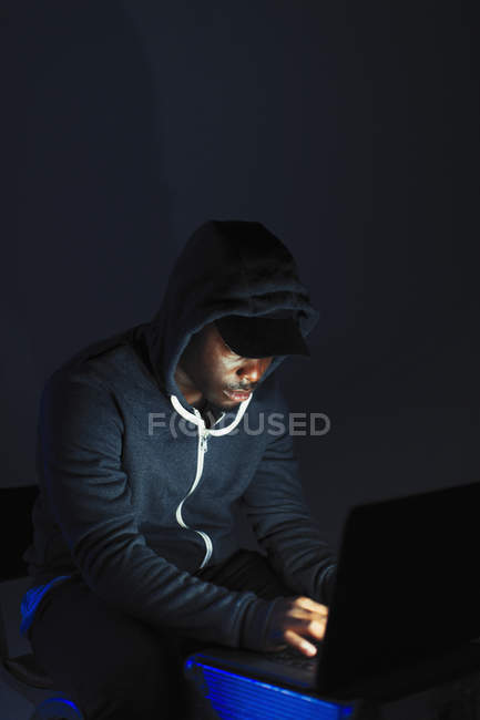 Мальчик в капюшоне сидит за ноутбуком — стоковое фото