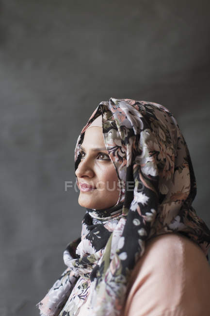 Serene, thoughtful woman in floral hijab looking up — Stock Photo