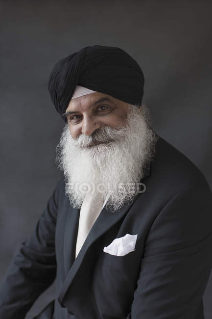 Retrato sonriente, confiado y bien vestido hombre mayor con barba en turbante - foto de stock