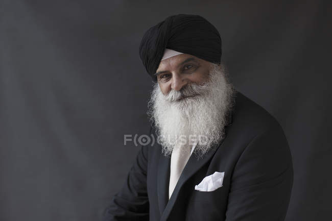 Portrait confident, well-dressed senior man with beard in turban — Stock Photo