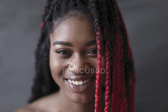 Портрет улыбается, уверенная молодая женщина с красными косичками — стоковое фото