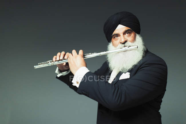 Well-dressed senior man in turban playing flute — Stock Photo