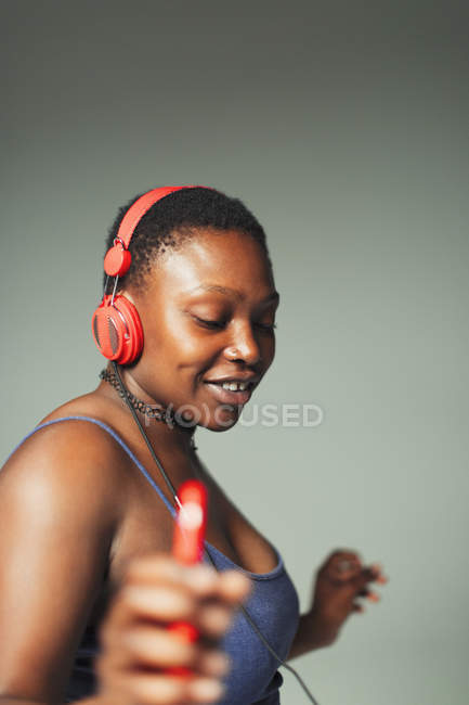 Mujer joven despreocupada con auriculares y reproductor de mp3 bailando - foto de stock