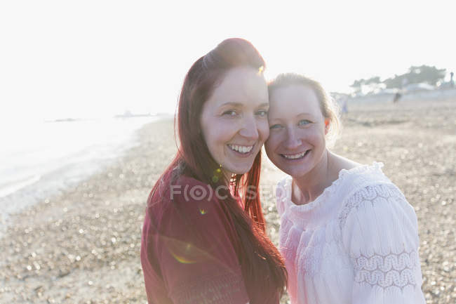 Ritratto sorridente, coppia lesbica affettuosa sulla spiaggia soleggiata — Foto stock
