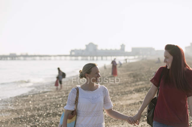 Casal lésbico afetuoso de mãos dadas na praia ensolarada — Fotografia de Stock