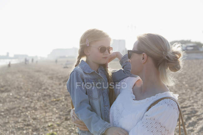 Mother and daughter wearing sunglasses on sunny beach — Stock Photo