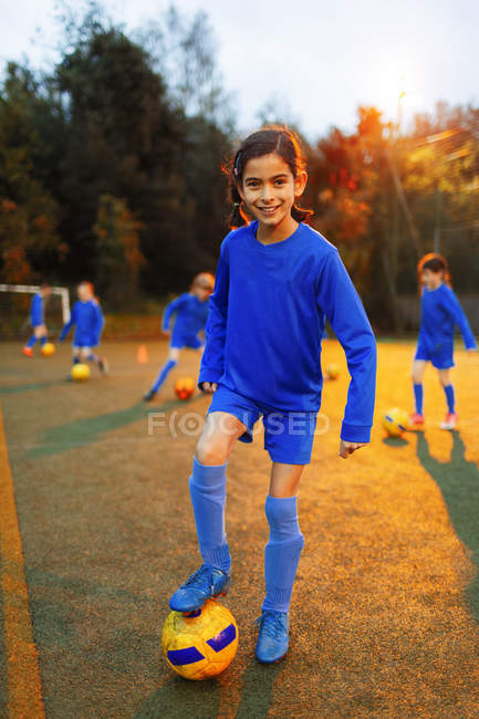 Portrait confident girl practicing soccer on field — Stock Photo