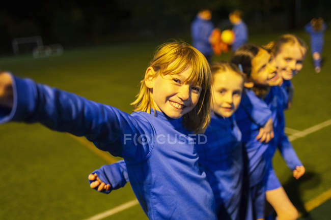 Portrait souriant, confiant filles équipe de soccer sur le terrain la nuit — Photo de stock