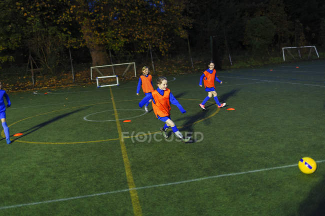 Equipe de futebol meninas praticando em campo à noite — Fotografia de Stock