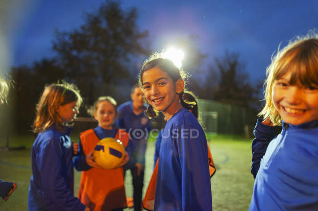 Портрет усміхнених дівчат футбольної команди на полі вночі — стокове фото