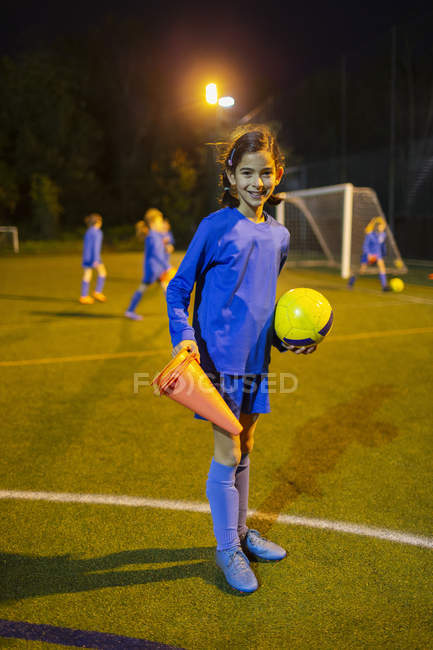Retrato confiante jogador de futebol menina em campo à noite — Fotografia de Stock