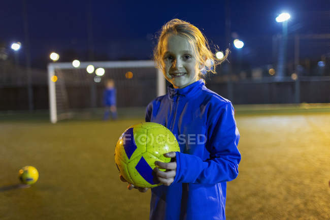 Retrato chica confiada futbolista en el campo por la noche - foto de stock