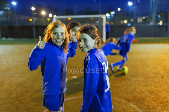 Портрет уверенной девушки, играющей в футбол, показывающей большие пальцы вверх — стоковое фото