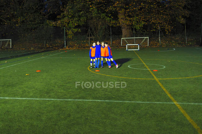 Ritratto fiducioso ragazze squadra di calcio sul campo di notte — Foto stock
