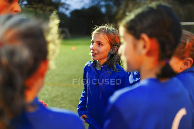 Atento equipo de fútbol niñas escuchando entrenador - foto de stock