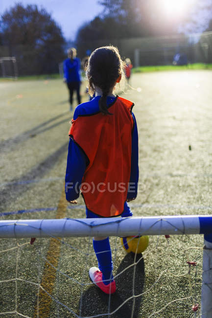 Girl playing soccer on field at night — Stock Photo