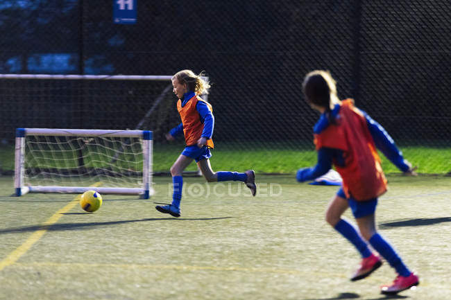 Meninas correndo, jogando futebol em campo — Fotografia de Stock