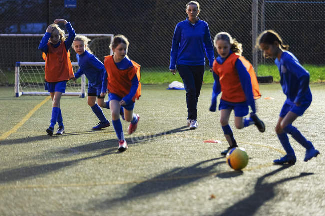 Fußballtrainer beobachtet Mädchen beim Training auf dem Feld — Stockfoto