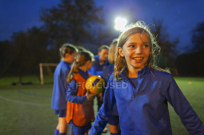 Portrait enthusiastic girl soccer players cheering on field at night — Stock Photo
