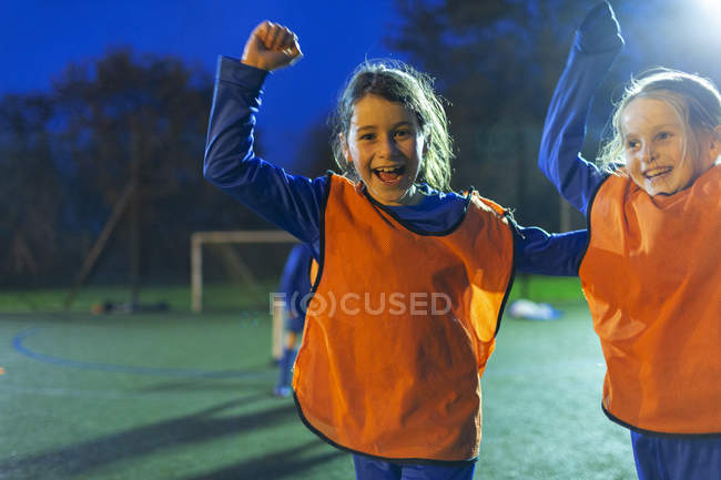 Retrato entusiasta menina jogadores de futebol torcendo em campo à noite — Fotografia de Stock