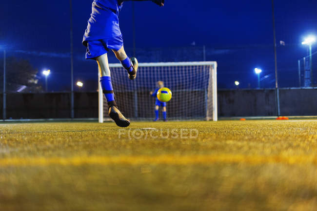 Menina jogador de futebol chutando bola em direção ao gol — Fotografia de Stock