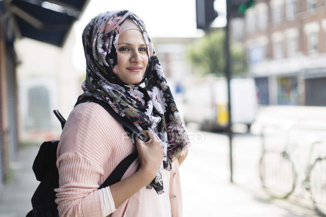 Retrato mujer confiada en hijab floral en la acera urbana - foto de stock