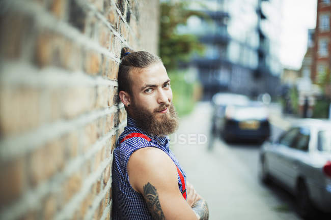 Confident male hipster on urban sidewalk — Stock Photo