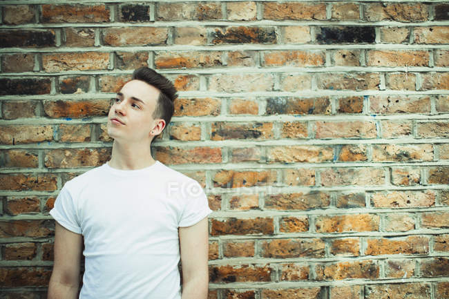 Thoughtful teenage boy standing at brick wall — Stock Photo
