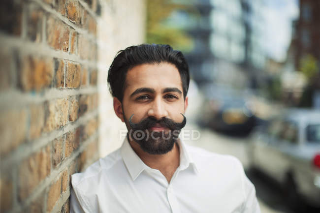 Portrait confident young man with handlebar mustache on urban sidewalk — Stock Photo