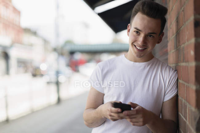 Adolescent garçon à l'aide de téléphone intelligent sur trottoir urbain — Photo de stock