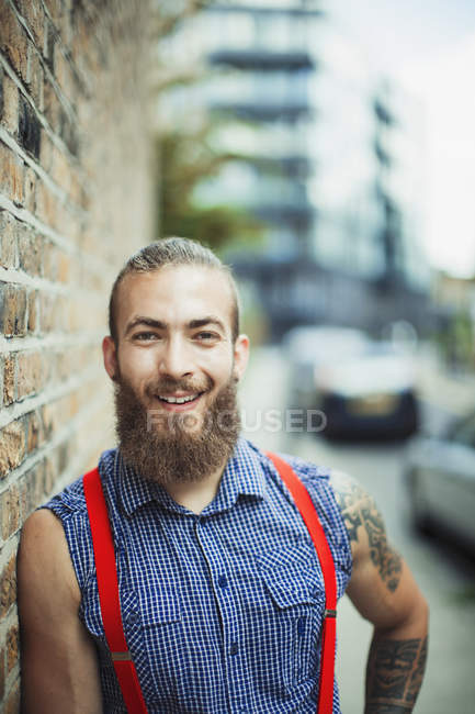 Portrait confident, smiling male hipster on urban sidewalk — Stock Photo