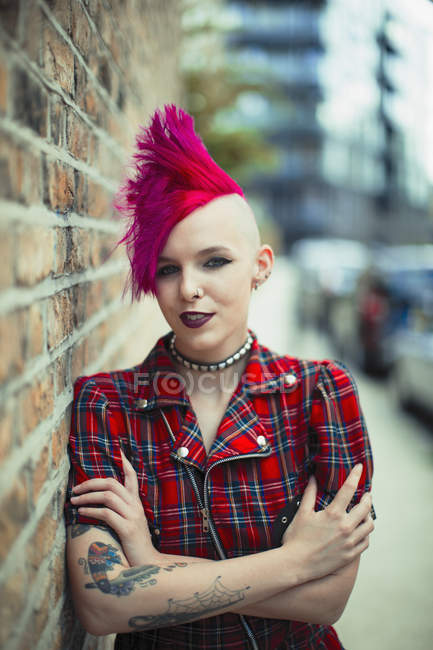 Retrato mujer joven confiada con mohawk rosa en la acera urbana - foto de stock